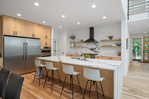 A modern kitchen with a large island, bar stools, and built-in appliances.