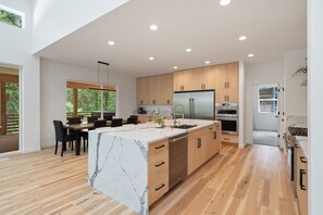 Una cocina moderna con armarios de madera, encimera de mármol y horno empotrado.
