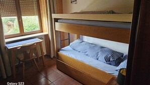 A bunk bed with a desk and chair, a window with blinds, and a small picture on the wall. - Etwas Älter Aber Fein (Villnöss)