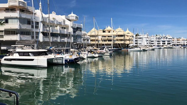 Un port de plaisance où sont amarrés de nombreux yachts, entouré d’immeubles à plusieurs étages dotés de balcons.