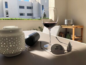 A table with a glass of red wine, a pair of sunglasses, a speaker, and a perforated container. - Apartment - Sleeps 4 - Parking - Garden - Pool (Alhaurin el Grande)