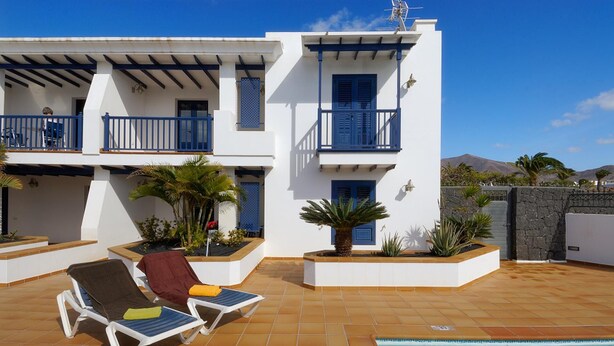 A two-story building with a pool, outdoor seating, and a view of mountains. - Immaculate 2-bed Apartment No 5 in Playa Blanca (Yaiza)