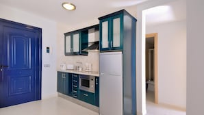 A kitchen with teal cabinets, a white refrigerator, and a microwave. - Immaculate 2-bed Apartment No 5 in Playa Blanca (Yaiza)