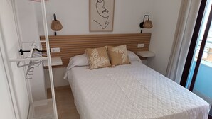 A neatly arranged bedroom with a large bed, a bedside table, a wall-mounted lamp, and a hanging rack. - Amazing & Renovated 2-bedroom Flat in Fuengirola (Fuengirola)