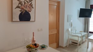 A living room with a dining area, a wooden door, a television, and a framed floral artwork on the wall. - Amazing & Renovated 2-bedroom Flat in Fuengirola (Fuengirola)