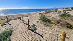 A wooden boardwalk leading to a sandy beach with a clear view of the ocean and distant mountains. - Luxury 2-bed Apartment Elviria - Pool, Sauna & gym (Marbella)