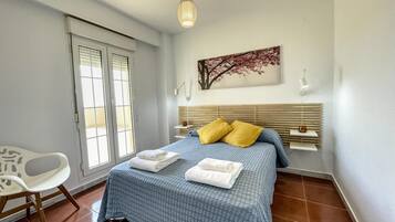 Une chambre à coucher avec un lit, une chaise, une fenêtre et un tableau accroché au mur.