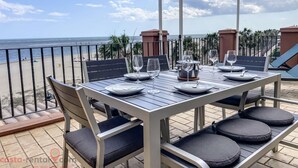 A terrace with a table set for two, overlooking a beach. - Luxury Front Line Apartment in Isla Canela Beach (Ayamonte)