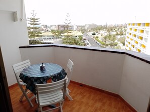 Ein Balkon mit Tisch und Stühlen mit Blick auf eine Stadtlandschaft mit Gebäuden und Palmen.