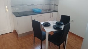 Cocina compacta con comedor, que incluye un lavamanos, encimera y una mesa con sillas para cuatro.