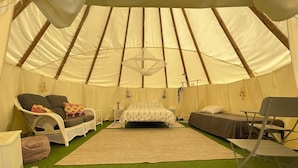 A tented room with a bed, two chairs, a small table, and a folding chair. - Beautiful Teepee With Private Facilities (Zujar)