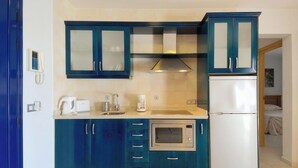A compact kitchen with teal cabinets, a built-in oven, a white refrigerator, and a coffee maker. - Impeccable 2-bed Apartment No 2 in Playa Blanca (Yaiza)