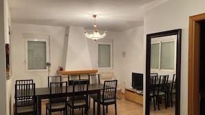 Ein Essbereich mit Tisch und Stühlen, einem Fernseher und einem Spiegel an der Wand.