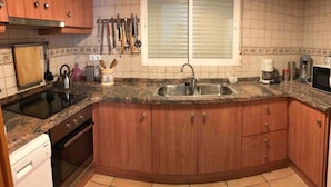 Eine Küche mit Holzausstattung, einer Granit-Arbeitsplatte, einem Backofen, einem Spülbecken und einem Fenster mit Jalousien.