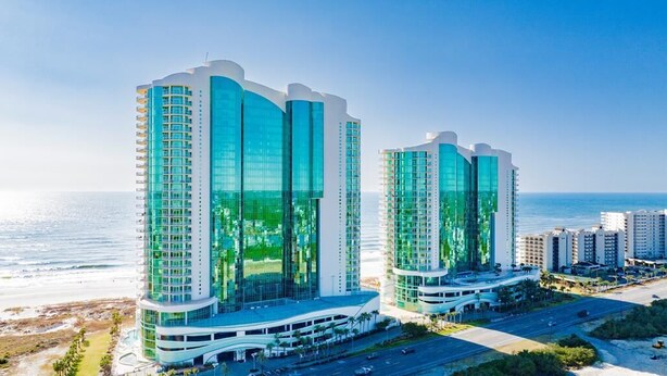 A modern hotel with a curved facade, large glass windows, and a beachfront location. - TURQUOISE Place.  3 bed 3 bath.  Sleeps 12. Balcony Hot Tub.  August 25% off. (Orange Beach)