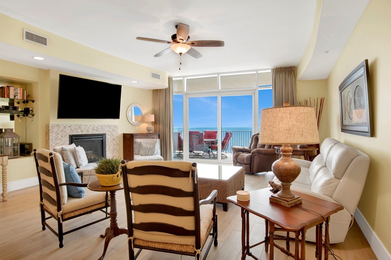 A spacious living room with a fireplace, a ceiling fan, and a view of the ocean.
