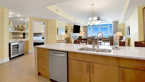 A modern kitchen with a central island, built-in dishwasher, and a dining area with a view. - TURQUOISE Place.  3 bed 3 bath.  Sleeps 12. Balcony Hot Tub.  August 25% off. (Orange Beach)