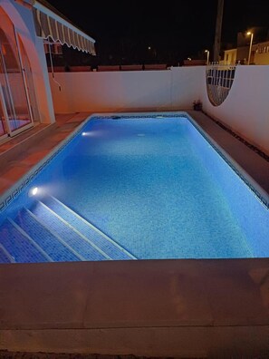 A rectangular swimming pool with a tiled edge, surrounded by a low wall and a small covered area with a white trim. - Casa Amira a Modern House With Pool (Pulpi)