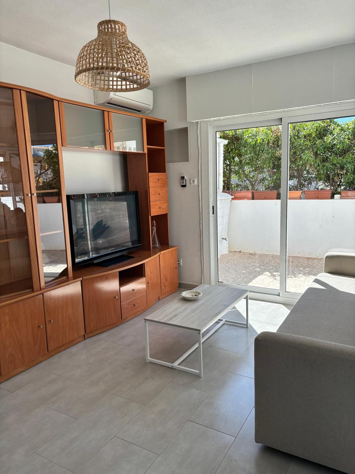 Un salon moderne avec un téléviseur à écran plat, un meuble de rangement en bois et une table basse en verre.