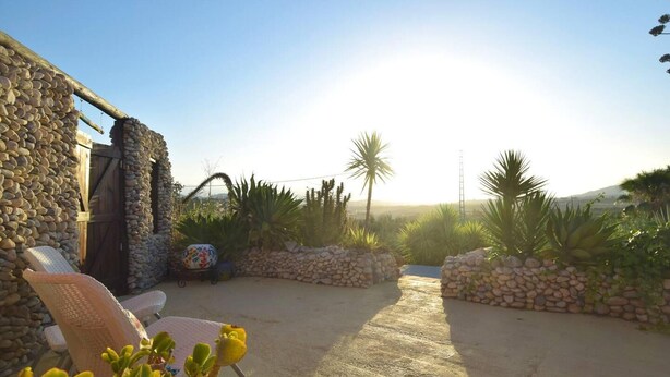 A patio area with stone walls, a wooden door, and a view of the landscape. - Fantastic View and Lovely Atmosphere Casita Adelfa (Alhaurin de la Torre)