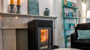 Una sala de estar acogedora con chimenea, una estantería azul turquesa y un sillón cómodo.