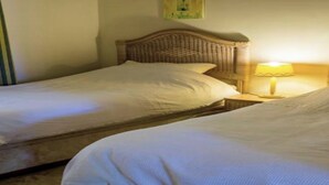 Une chambre d’hôtel avec deux lits simples, une tête de lit en bois, une lampe de chevet et une petite table.
