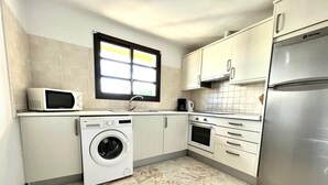 A compact kitchen with a washing machine, microwave, oven, and refrigerator. - House - Sleeps 6 - Pool - Pet Friendly (La Oliva)