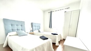 A hotel room with two beds, a wardrobe, and a small desk. - House - Sleeps 6 - Pool - Pet Friendly (La Oliva)