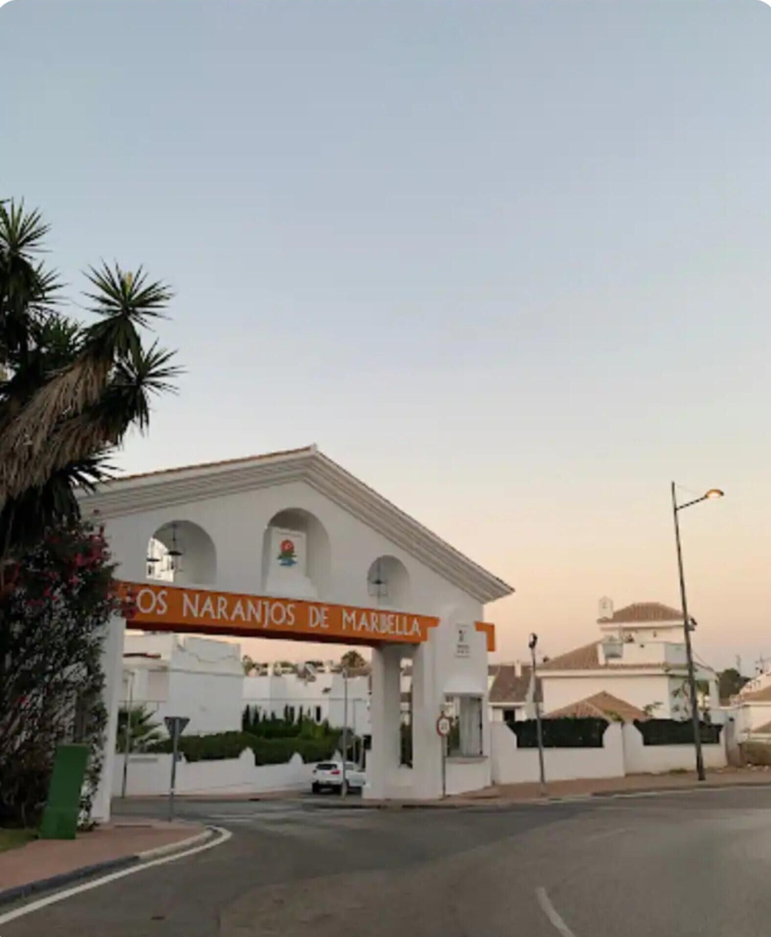 A white building with a sign reading "OS NARANJOS DE MARBELLA" at the entrance.
