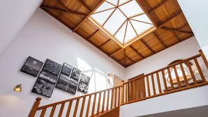 Un escalier en bois, surmonté d’une lucarne, mène à l’étage supérieur.