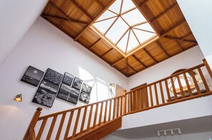 Un escalier en bois, surmonté d’une lucarne, mène à l’étage supérieur.