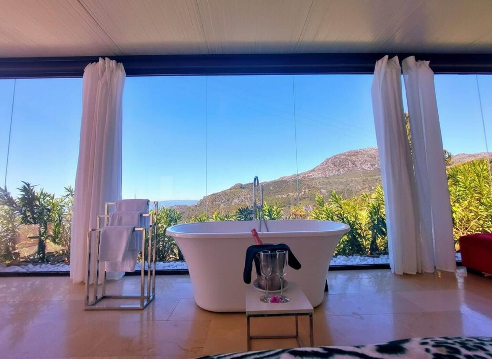 Ein modernes Badezimmer mit einer freistehenden Badewanne, einer Duschkabine aus Glas und Bergblick durch große Fenster.