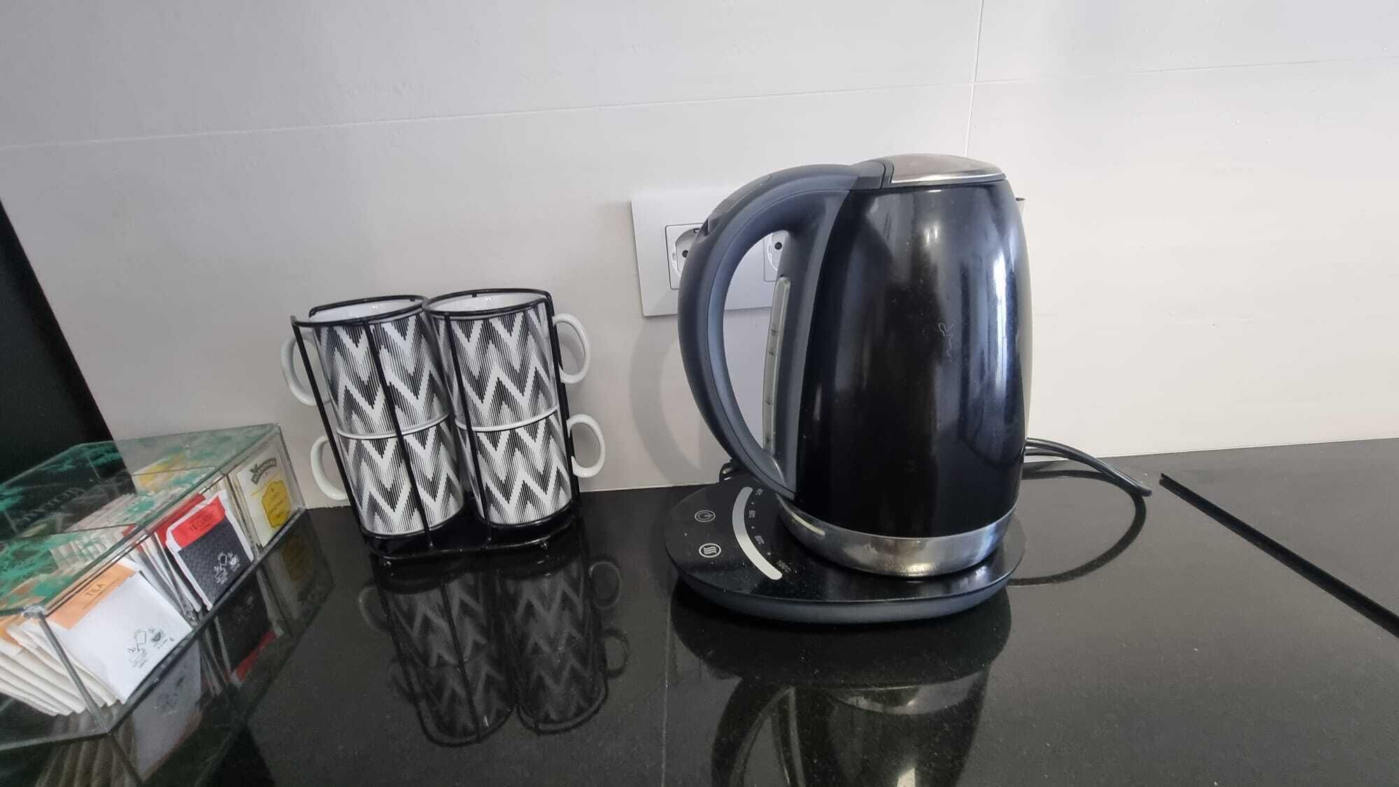 Una encimera de cocina con un hervidor y dos tazas decoradas.