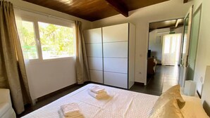 Une chambre d’hôtel comprenant un lit, une armoire, une salle de bain et donnant sur l’extérieur.