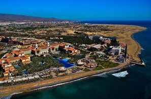 An aerial view of a coastal resort with multiple buildings, a beach, and a pier. - Renovated Apartment by the Beach and Yumbo Centre (San Bartolomé de Tirajana)