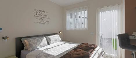 A hotel room with a bed, a ceiling fan, a window with blinds, a desk, and a chair.