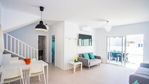 Ein modernes Wohnzimmer mit Essbereich, einem grauen Sofa und einer Treppe, die zu einer weiteren Ebene führt.