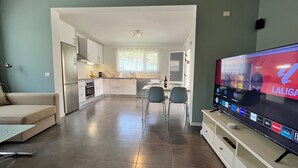 A modern living room with a flat-screen TV, a sofa, a dining area, and a kitchen in the background. - Large Country House Near Maspalomas & Fataga (San Bartolomé de Tirajana)