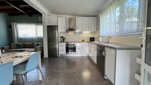 A modern kitchen with white cabinets, stainless steel appliances, and a dining area with a table and chairs. - Large Country House Near Maspalomas & Fataga (San Bartolomé de Tirajana)