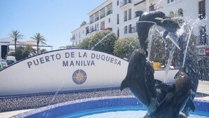 Un panneau indiquant « Puerto de la Duquesa Manilva », avec une fontaine décorative en premier plan.
