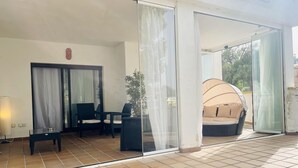 Une pièce baignée de lumière naturelle, dotée d’une porte vitrée, d’un coin salon avec des coussins et d’une plante en pot.