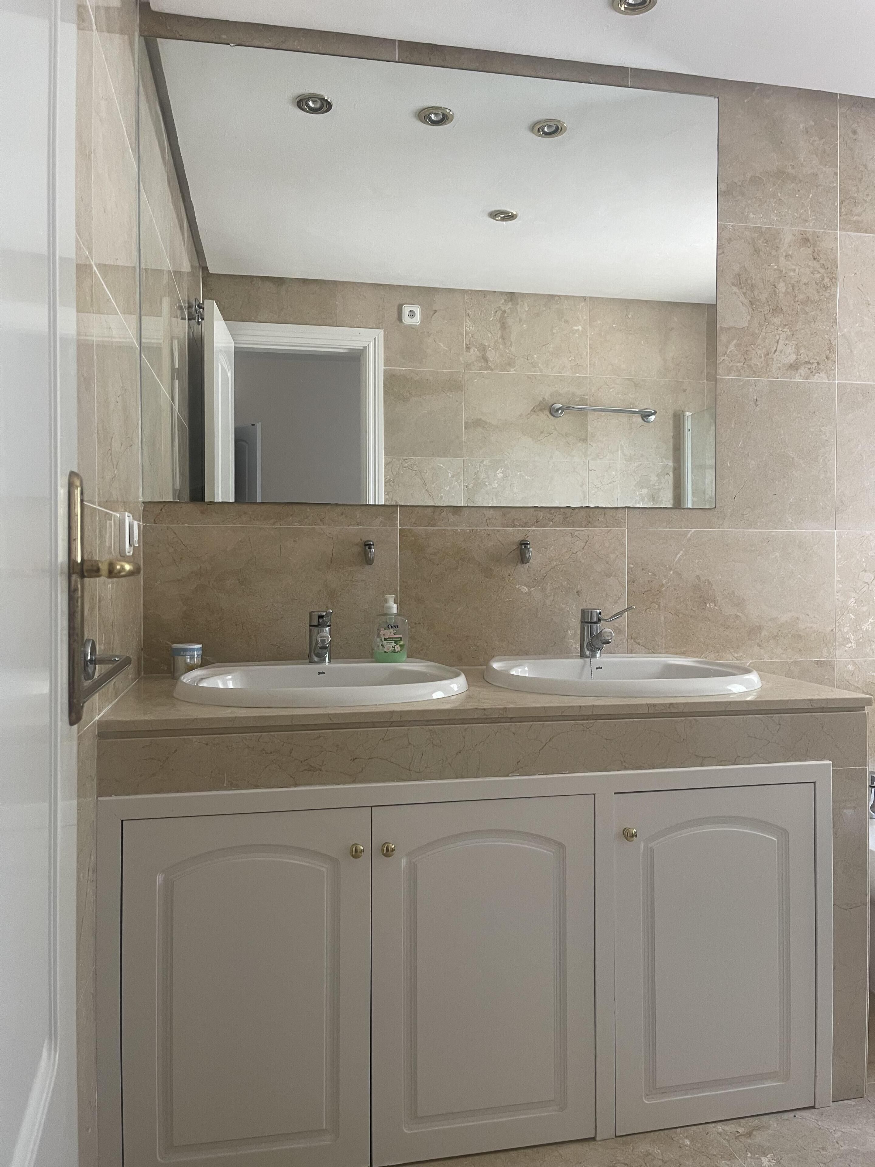 A bathroom with two sinks, a large mirror, and a towel rack.