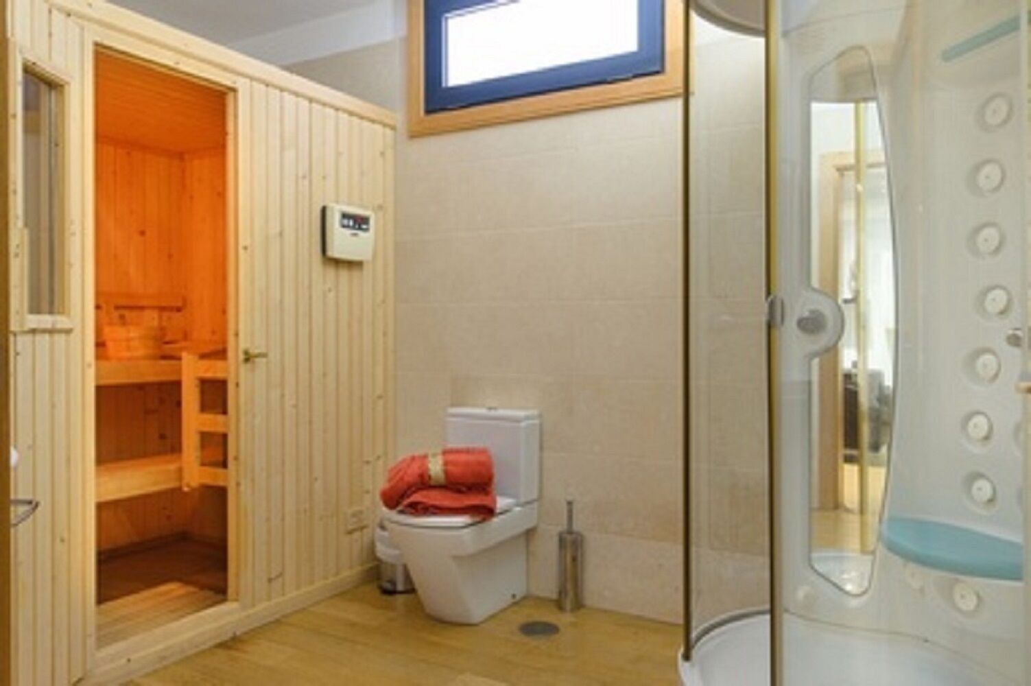 Ein Saunaraum mit einer Holzbank, einer Toilette und einem Duschbereich.