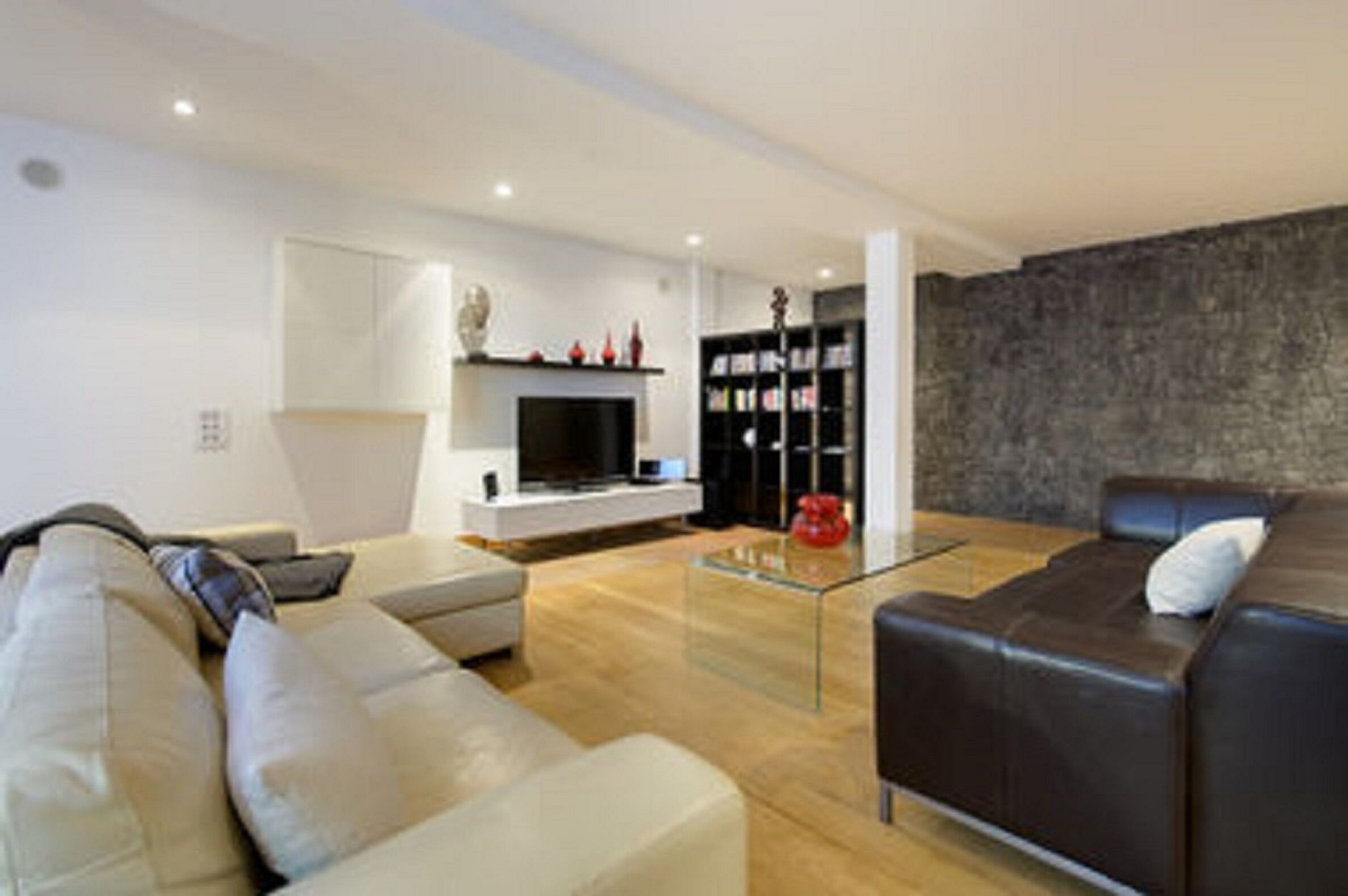 Una sala moderna con un sofá, una mesa de centro de vidrio, una chimenea y una estantería.