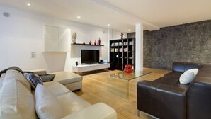 Ein modernes Wohnzimmer mit einer Couch, einem Glastisch, einem Kamin und einem Bücherregal.