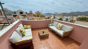 A rooftop terrace with two sofas and a wooden coffee table, featuring a cityscape view. - 2 Bed House - Sleeps 4 - Pool - Terrace - Parking (Pulpi)