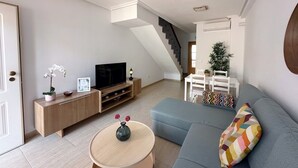 A modern living room with a flat-screen TV, a sofa, a coffee table, and a staircase leading to another level. - 2 Bed House - Sleeps 4 - Pool - Terrace - Parking (Pulpi)