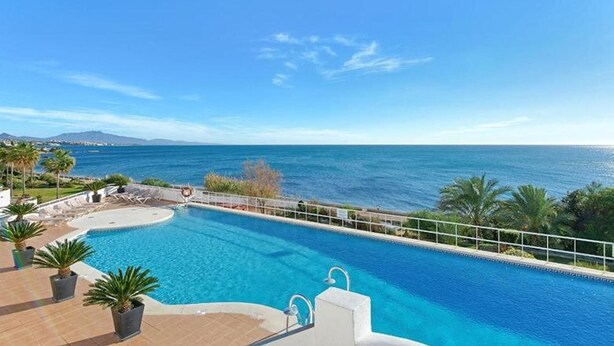 Piscina com vista para o mar e montanhas.