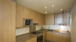 Uma cozinha com armários de madeira, micro-ondas, pia e janela.