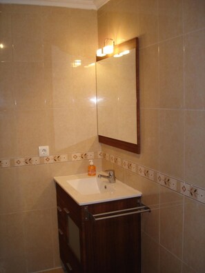 A bathroom with a sink, mirror, and towel rack.